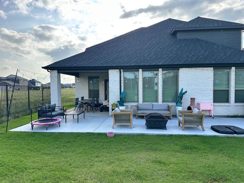 Rear view of property with an outdoor living space with a fire pit, a shingled roof, and brick siding