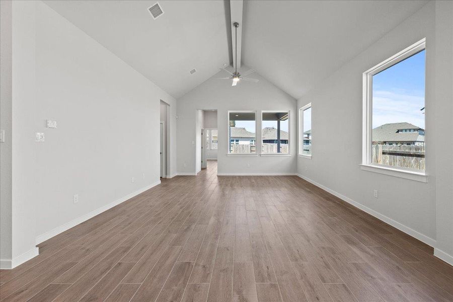 Unfurnished living room with beamed ceiling, ceiling fan, wood finished floors, and high vaulted ceiling Unfurnished living room with beamed ceiling, ceiling fan, wood finished floors, and high vaulted ceiling