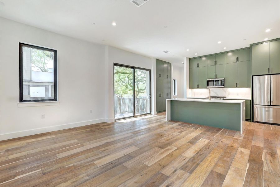 Kitchen with stainless steel appliances, green cabinets, plenty of natural light, light wood-style flooring, and recessed lighting