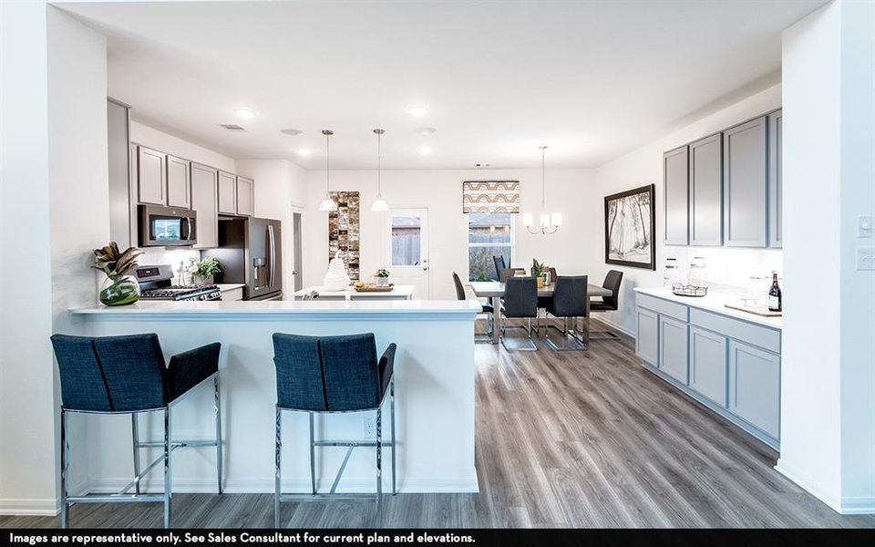 Open-concept kitchen and dining area featuring light gray cabinetry, white countertops, stainless steel appliances, wood-finish flooring, and recessed lighting Open-concept kitchen and dining area featuring light gray cabinetry, white countertops, stainless steel appliances, wood-finish flooring, and recessed lighting