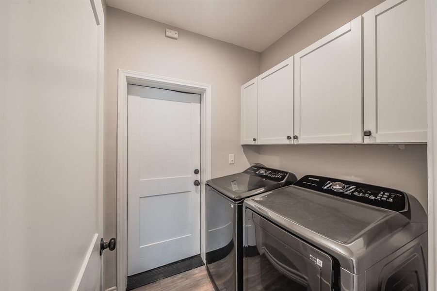 Laundry area with light wood-style flooring, cabinet space, and separate washer and dryer Laundry area with light wood-style flooring, cabinet space, and separate washer and dryer