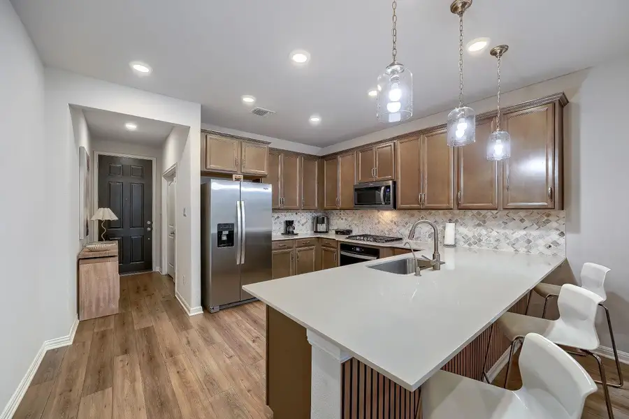 Kitchen featuring stainless steel appliances, wood-finish cabinetry, and a patterned tile backsplash