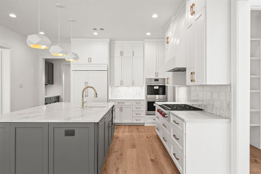 Kitchen with decorative light fixtures, light stone countertops, white cabinets, light wood-type flooring, and gray cabinets Kitchen with decorative light fixtures, light stone countertops, white cabinets, light wood-type flooring, and gray cabinets