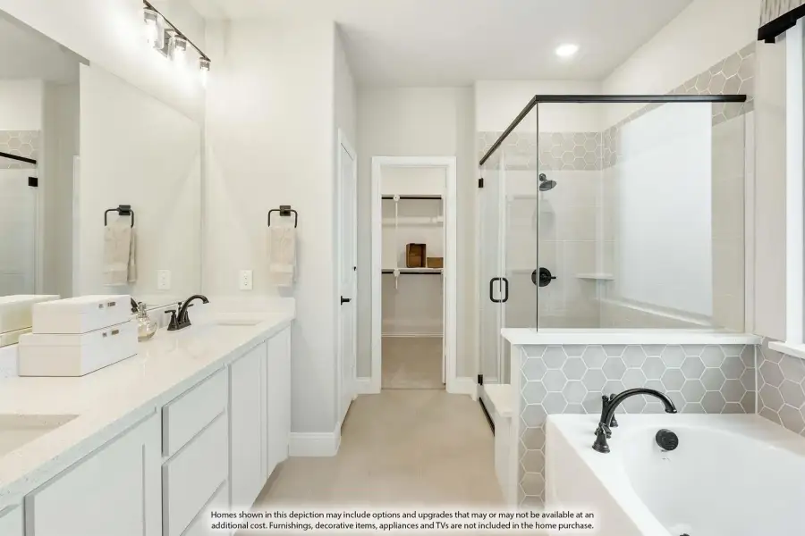 Master bathroom with double vanity, soaking tub, glass shower, and walk-in closet access
