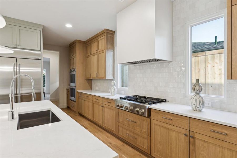 Kitchen featuring light countertops, appliances with stainless steel finishes, light wood-style floors, tasteful backsplash, and recessed lighting