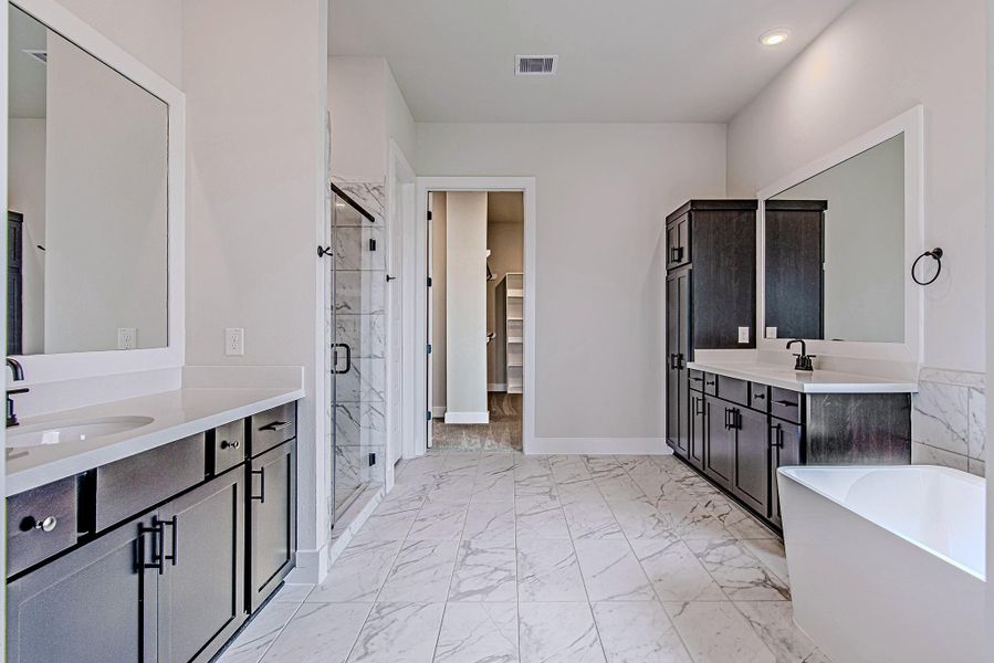 Primary bathroom with dual vanities, soaking tub, and separate shower.