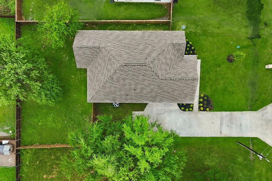 Aerial perspective showcasing a gabled roofline, concrete driveway, and expansive green lawn