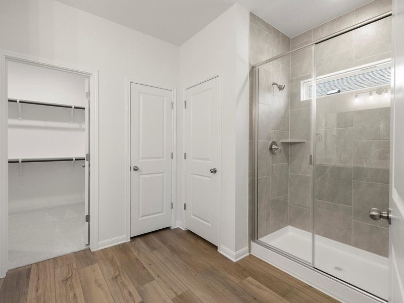 This primary bathroom features a generous glass-enclosed shower, two doors, and an open closet for practical daily use.