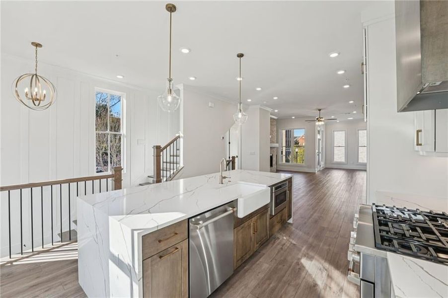 Kitchen featuring stainless steel appliances, light stone countertops, dark wood finished floors, healthy amount of natural light, and recessed lighting Kitchen featuring stainless steel appliances, light stone countertops, dark wood finished floors, healthy amount of natural light, and recessed lighting