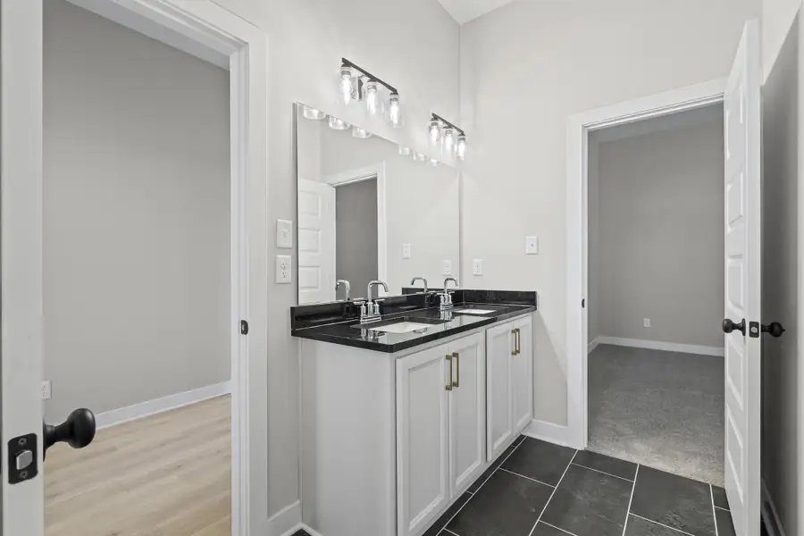 Full bathroom with double vanity and dark tile patterned flooring