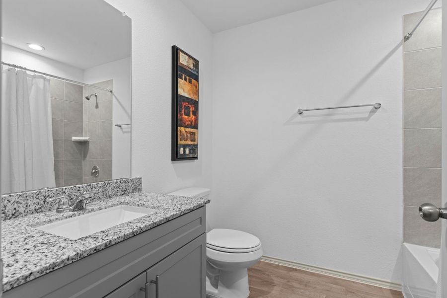 Full secondary bathroom with sleek granite vanity, undermount sink, and modern fixtures — perfectly placed to serve guests and additional bedrooms. Full secondary bathroom with sleek granite vanity, undermount sink, and modern fixtures — perfectly placed to serve guests and additional bedrooms.