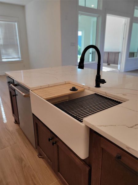 This kitchen features a modern island with a sleek quartz countertop, deep farmhouse sink, and stylish black faucet. The open layout and natural lighting create a bright, inviting space. This kitchen features a modern island with a sleek quartz countertop, deep farmhouse sink, and stylish black faucet. The open layout and natural lighting create a bright, inviting space.