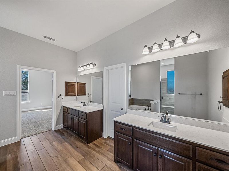 Prior listing photo. Property remains accurate - Bathroom with two vanities and dark wood-style floors