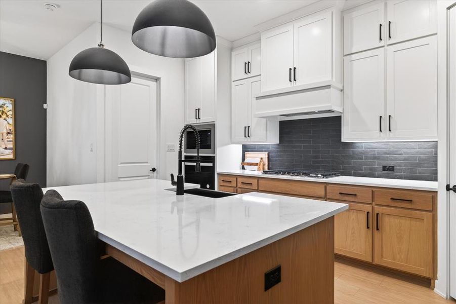 Kitchen with brown cabinetry, light stone countertops, tasteful backsplash, light wood-style flooring, and white cabinets Kitchen with brown cabinetry, light stone countertops, tasteful backsplash, light wood-style flooring, and white cabinets