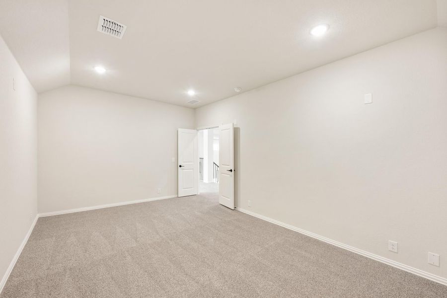 Empty bedroom with gray carpet, white walls, and open double doors leading to hallway