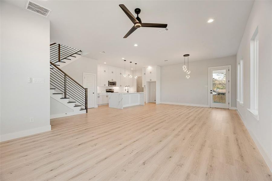 Unfurnished living room with stairway, ceiling fan, light wood-style floors, and recessed lighting Unfurnished living room with stairway, ceiling fan, light wood-style floors, and recessed lighting