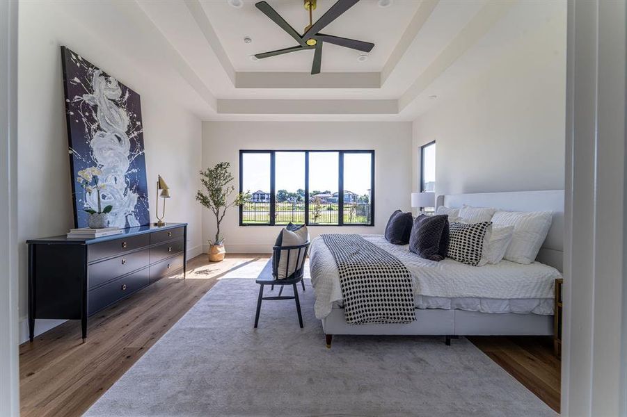 Bedroom featuring ceiling fan, a raised ceiling, and hardwood / wood-style flooring