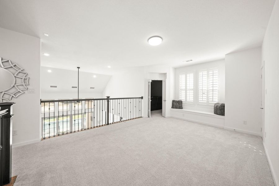 The game room features soft carpet, a balcony overlooking the family room with wrought-iron spindles, windows with plantation shutters, a window seat and a separate 9’ x 6’ storage closet.