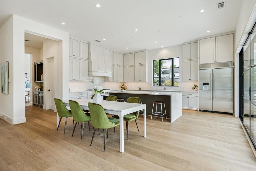The casual dining off of the kitchen has access to the butler pantry and bar.  Door to the hidden pantry/prep area can be seen in the bar area.