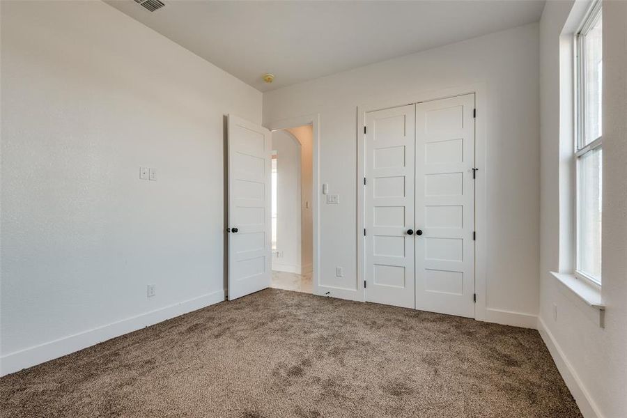 Unfurnished bedroom featuring a closet, multiple windows, and carpet floors