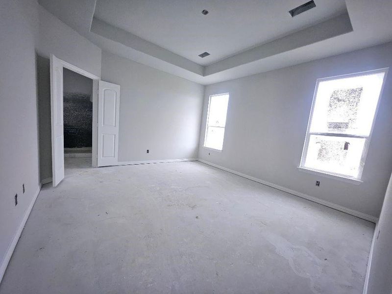 Spacious room featuring a tray ceiling, two large windows, white trim, and a double-door entry Spacious room featuring a tray ceiling, two large windows, white trim, and a double-door entry
