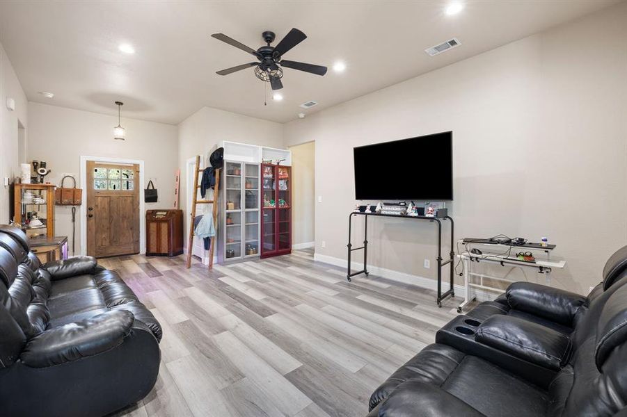 Living room with ceiling fan and light hardwood / wood-style flooring