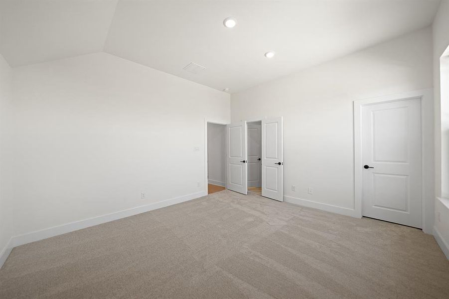 Unfurnished bedroom with light colored carpet, recessed lighting, and lofted ceiling Unfurnished bedroom with light colored carpet, recessed lighting, and lofted ceiling