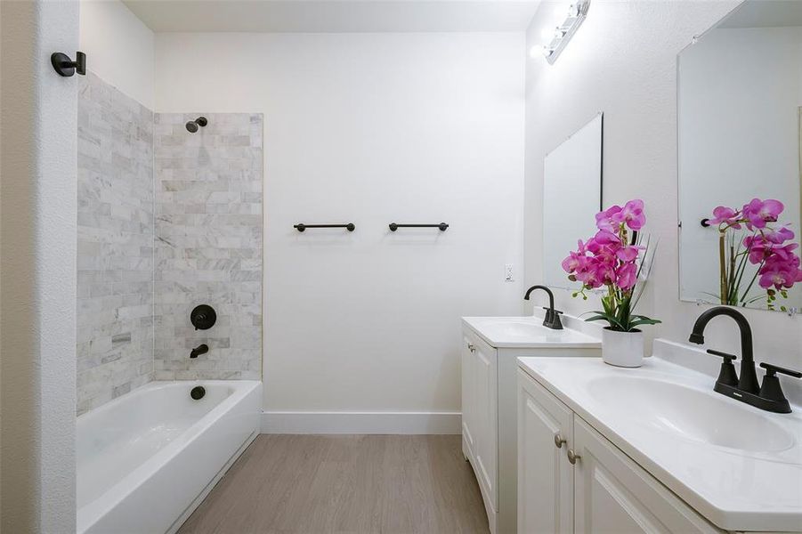 Bathroom featuring tiled shower / bath combo, vanity, and hardwood / wood-style flooring