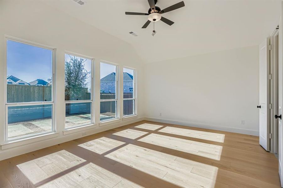 Empty room featuring light wood-type flooring, ceiling fan, and vaulted ceiling Empty room featuring light wood-type flooring, ceiling fan, and vaulted ceiling