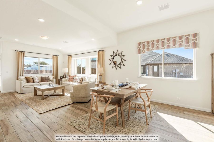 Open-plan living and dining area with wood-look floors, neutral furnishings, and large windows letting in natural light.