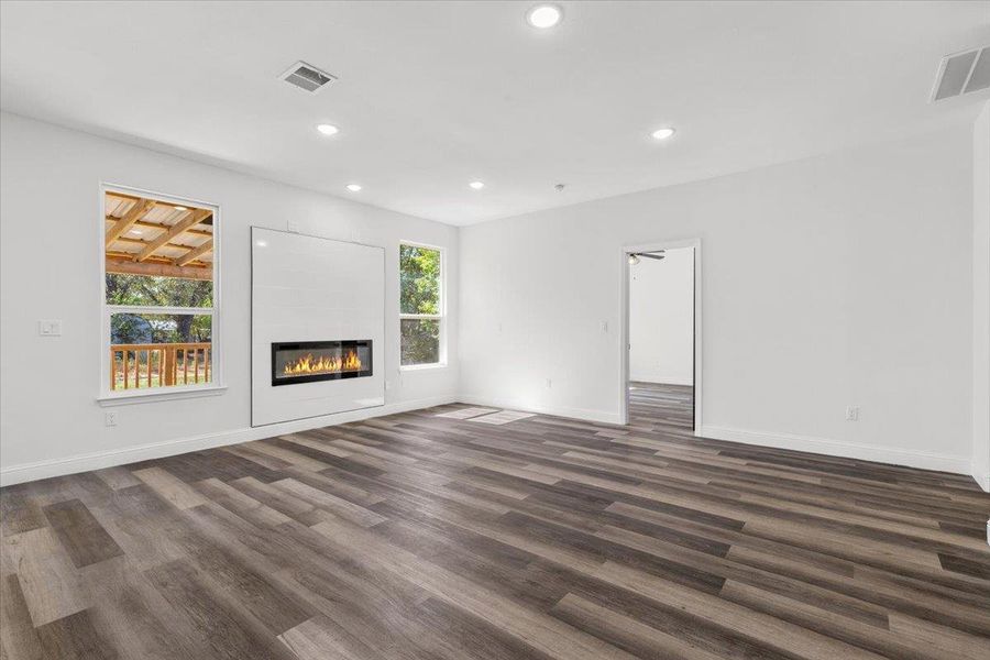 Rich wood plank flooring and a modern linear fireplace anchor this open living area. Rich wood plank flooring and a modern linear fireplace anchor this open living area.