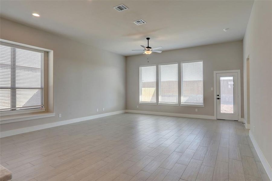 Empty room featuring ceiling fan, light hardwood / wood-style floors, and a wealth of natural light