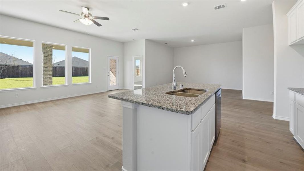 Kitchen featuring white cabinets, open floor plan, light wood-style flooring, dark stone countertops, and recessed lighting
