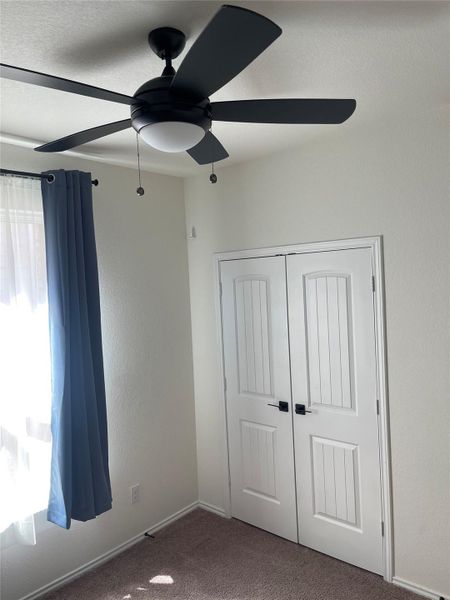 Unfurnished bedroom featuring carpet floors, a closet, a textured wall, ceiling fan, and a textured ceiling Unfurnished bedroom featuring carpet floors, a closet, a textured wall, ceiling fan, and a textured ceiling