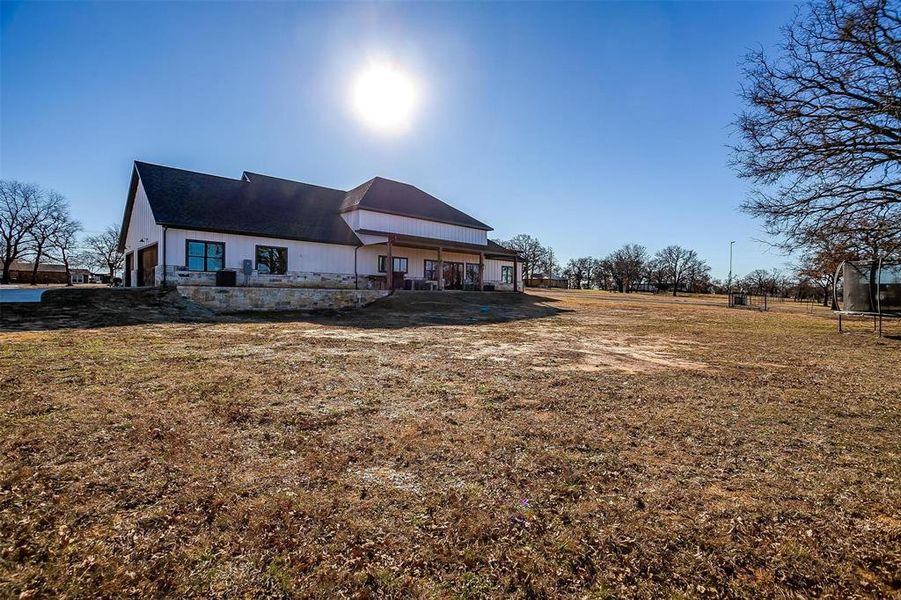 Back of house featuring a trampoline and a lawn