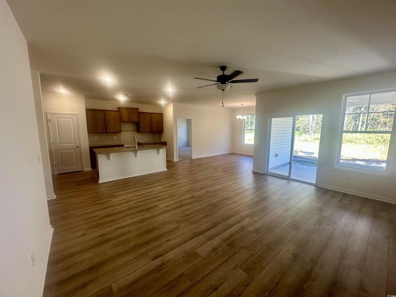 Unfurnished living room with a chandelier, a ceiling fan, and dark wood-style flooring