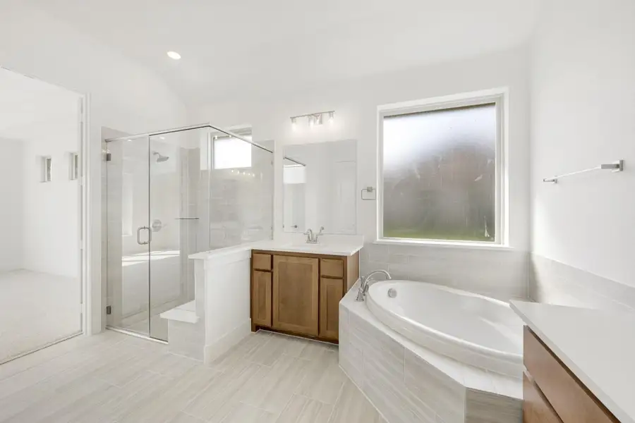 Master bathroom with corner soaking tub, glass walk-in shower, wood vanity, and vaulted ceiling Master bathroom with corner soaking tub, glass walk-in shower, wood vanity, and vaulted ceiling