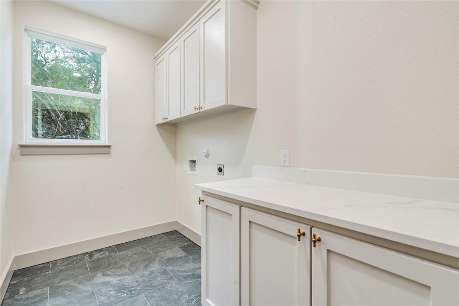 Washroom with hookup for a washing machine, hookup for an electric dryer, cabinet space, and hookup for a gas dryer