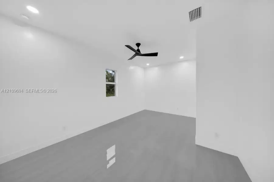 Interior space featuring neutral wall tones, wood-finish flooring, recessed lighting, and a matte black ceiling fan