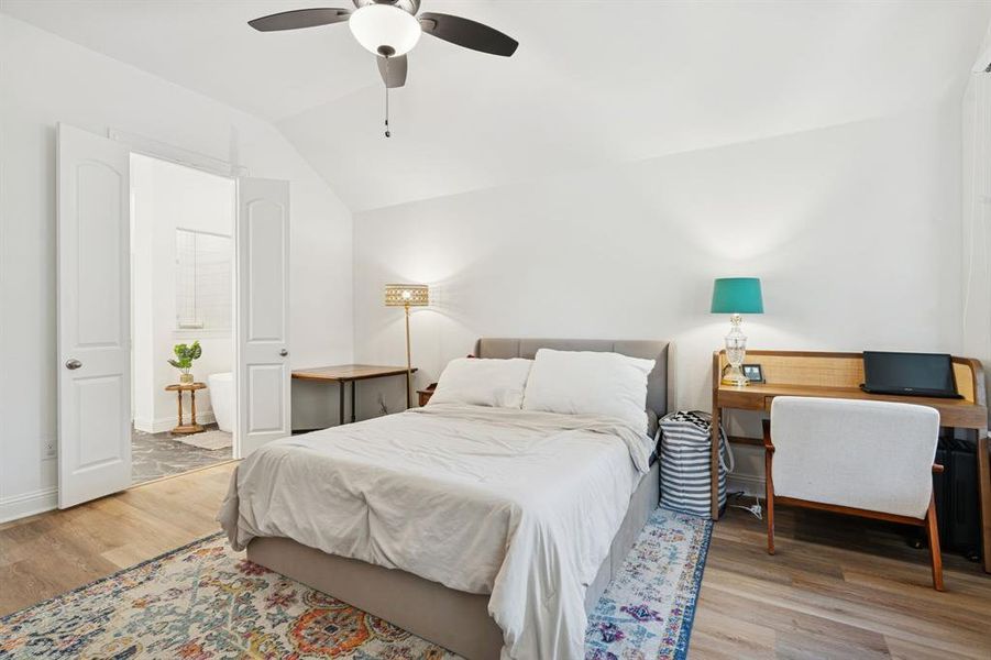 Bedroom with light wood-type flooring, a ceiling fan, vaulted ceiling, ensuite bathroom, and a desk Bedroom with light wood-type flooring, a ceiling fan, vaulted ceiling, ensuite bathroom, and a desk