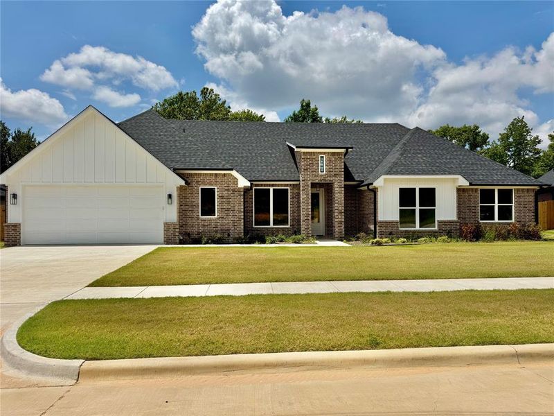 View of front of house featuring a shingled roof, a front yard, board and batten siding, and driveway