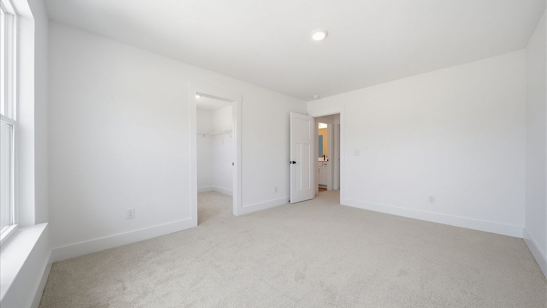 Elegant bedroom retreat featuring soft carpeting and a thoughtfully designed walk-in closet Elegant bedroom retreat featuring soft carpeting and a thoughtfully designed walk-in closet