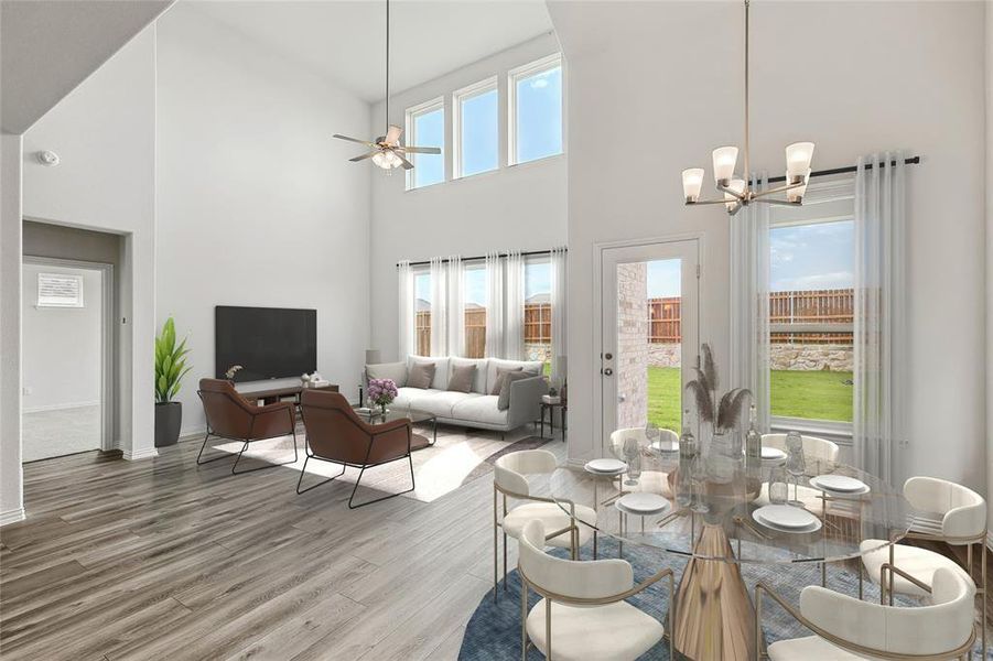 Dining space featuring a towering ceiling, a healthy amount of sunlight, hardwood / wood-style flooring, and ceiling fan with notable chandelier