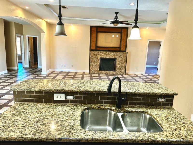 Kitchen with a tiled fireplace, ceiling fan, sink, and hanging light fixtures