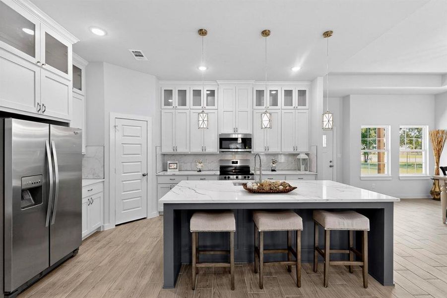Kitchen with stainless steel appliances, decorative backsplash, glass insert cabinets, light stone countertops, and a breakfast bar Kitchen with stainless steel appliances, decorative backsplash, glass insert cabinets, light stone countertops, and a breakfast bar