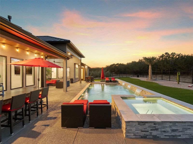 Pool at dusk with a fenced backyard, a patio, an outdoor living space, and a pool with connected hot tub