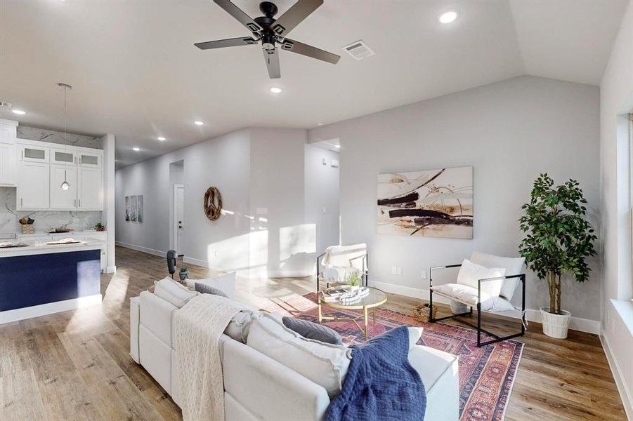 Living room featuring ceiling fan, lofted ceiling, and light hardwood / wood-style flooring