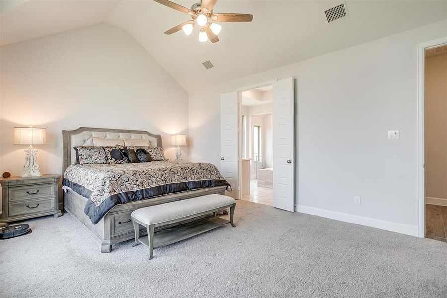 Carpeted bedroom with baseboards, a ceiling fan, connected bathroom, and high vaulted ceiling Carpeted bedroom with baseboards, a ceiling fan, connected bathroom, and high vaulted ceiling