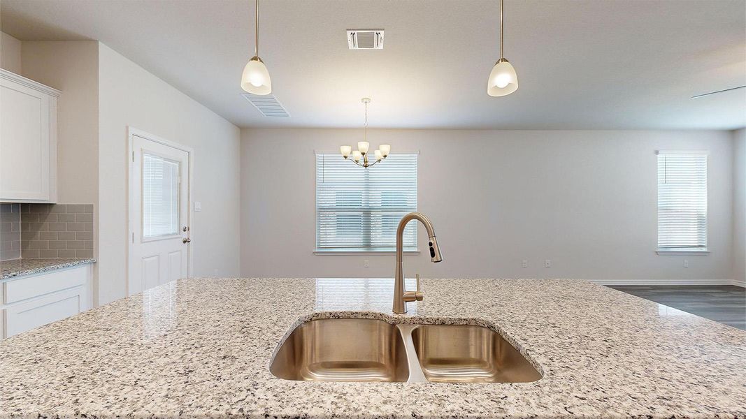 Kitchen featuring light stone counters, backsplash, and healthy amount of natural light