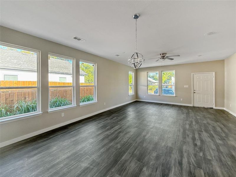 Unfurnished living room with dark wood finished floors, a chandelier, and a ceiling fan